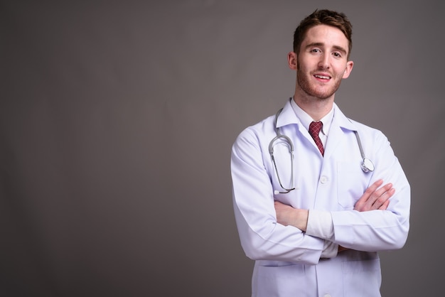 Médico joven guapo contra gris