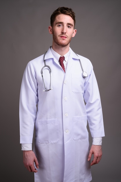 Médico joven guapo contra gris