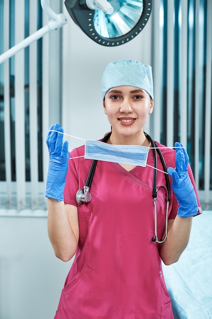 Médico joven hermosa en uniforme blanco y máscara