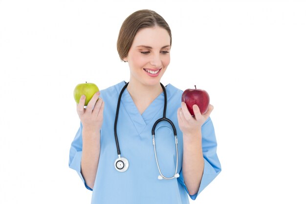 Médico joven manteniendo dos manzanas