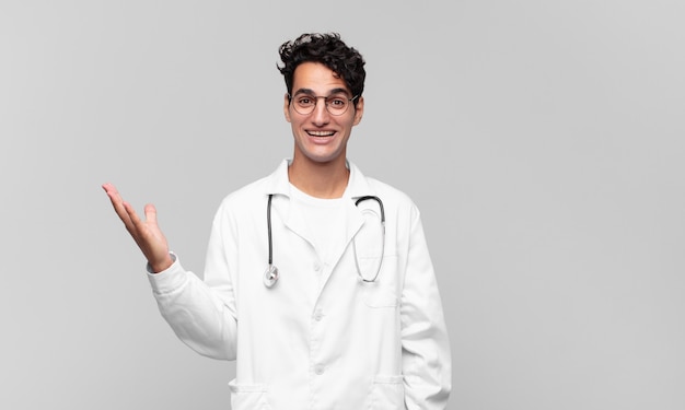 Médico joven que se siente feliz, sorprendido y alegre, sonriendo con actitud positiva, dándose cuenta de una solución o idea