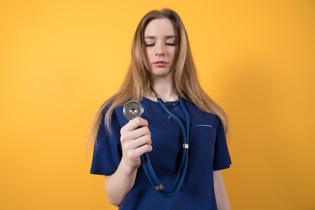 Un médico joven en el traje quirúrgico sobre un fondo amarillo