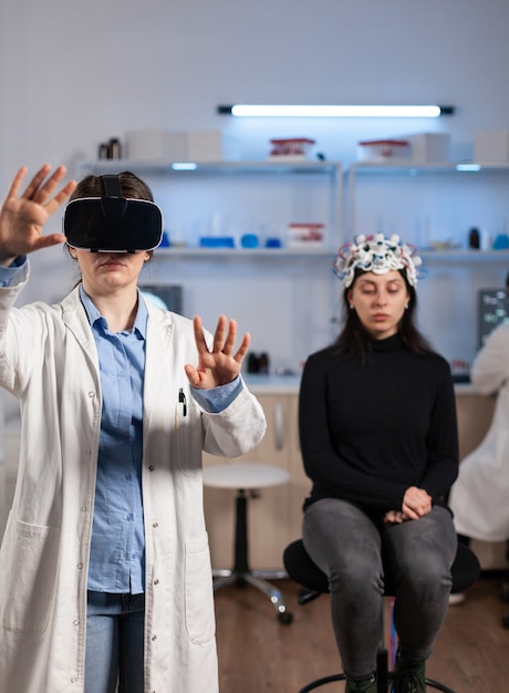 Médico de laboratorio experimentando la realidad virtual usando gafas vr en el laboratorio de investigación neurológica médica. Médico terapeuta con gafas de dispositivo de equipo de innovación médica, analizando el escáner cerebral.