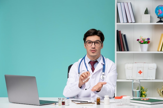 Médico lindo médico inteligente en bata de laboratorio trabajando de forma remota en la computadora desinfectando las manos