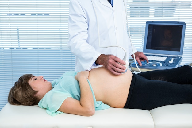 Médico macho realizando ultra-som em mulher grávida