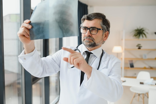 Médico mais velho examina imagem de raio-x dos pulmões em uma clínica