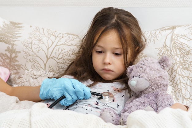 Foto médico mão na luva médica ouvindo pulmão de menina doente com estetoscópio retrato de criança doente