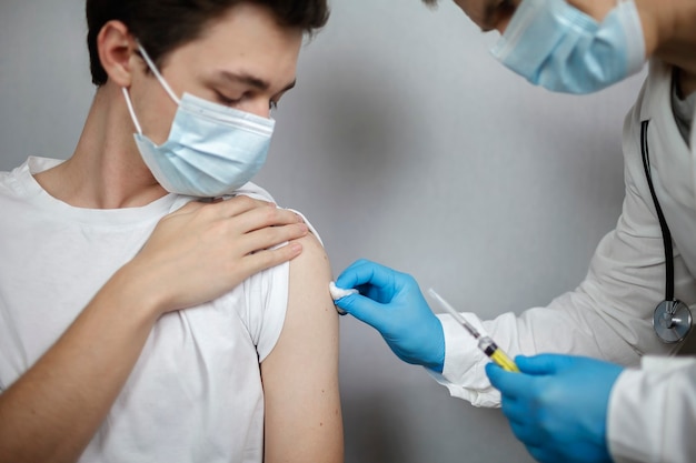 Médico con máscara médica y guantes con ampolla y jeringa con vacuna contra el coronavirus