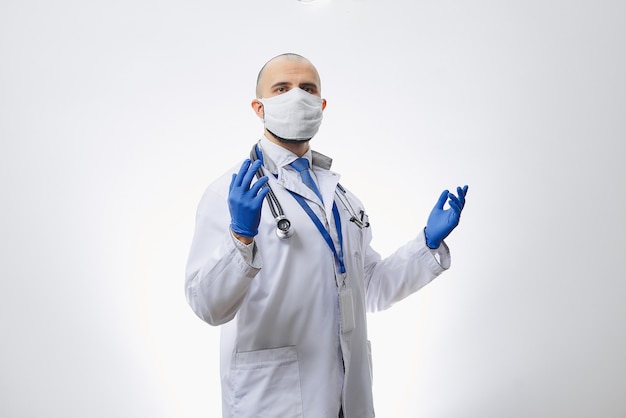 Un médico con una mascarilla protectora para evitar la propagación del coronavirus con las manos en guantes médicos desechables.