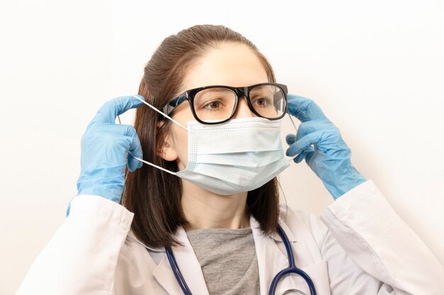 Médico con mascarilla protectora y guantes de látex contra el coronavirus. Equipo preventivo del personal médico del panorama de la bandera.