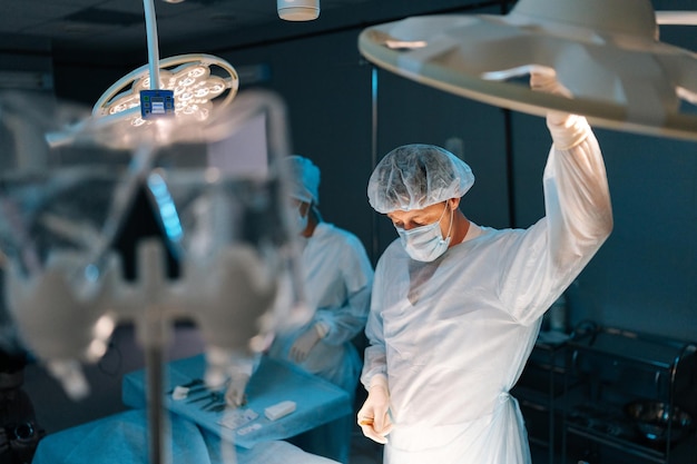 Foto médico masculino ajustando la luz realizando una operación en túnica médica operación quirúrgica por un profesional