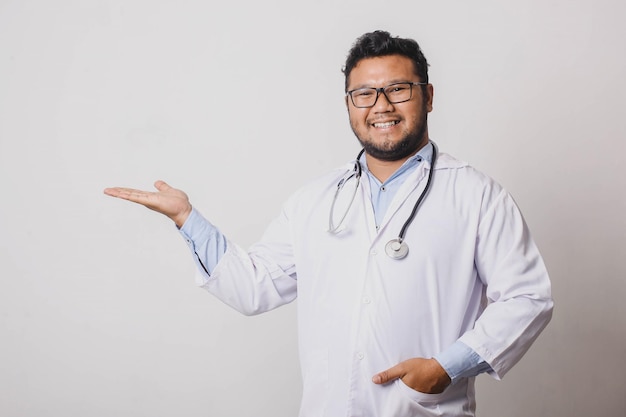 Médico masculino alegre apresentando lateralmente isolado no fundo branco com espaço de cópia