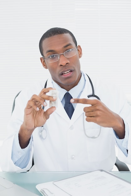 Médico masculino apontando para a garrafa de prescrição