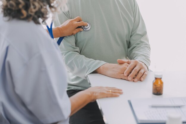 Foto médico masculino asiático maduro falando com seu paciente explicando o procedimento para a velhota