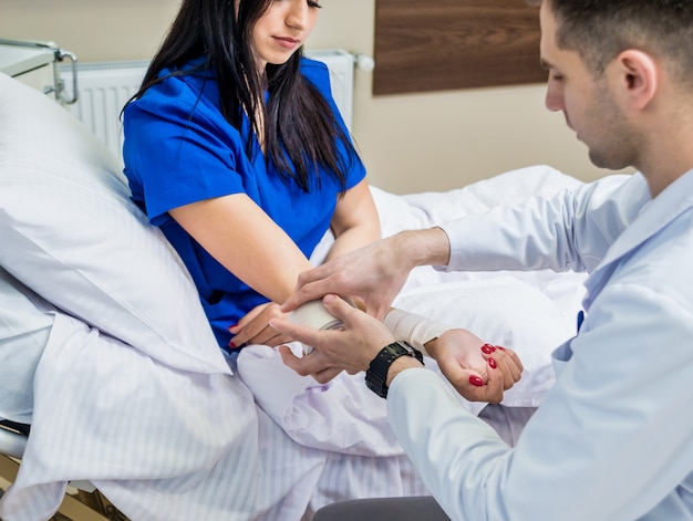 Médico masculino bandagem mão de pacientes do sexo feminino.