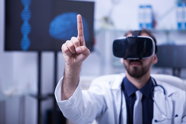 Foto médico masculino con bata blanca usando un casco de realidad virtual. médico masculino en el hospital usando gafas de realidad virtual.