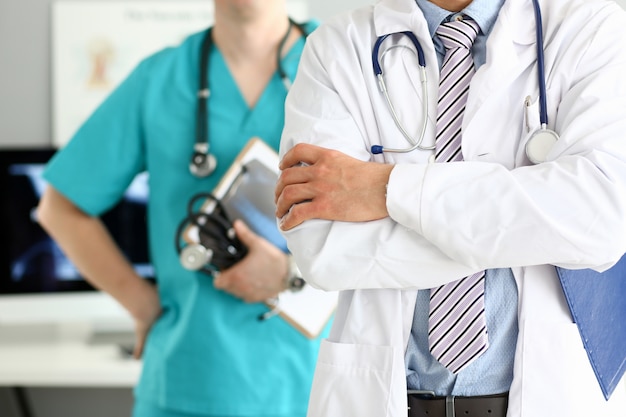 Médico masculino com os braços cruzados no peito em pé na fila com os colegas no escritório