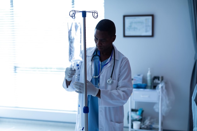 Médico masculino comprobando el goteo de terapia intravenosa en la sala