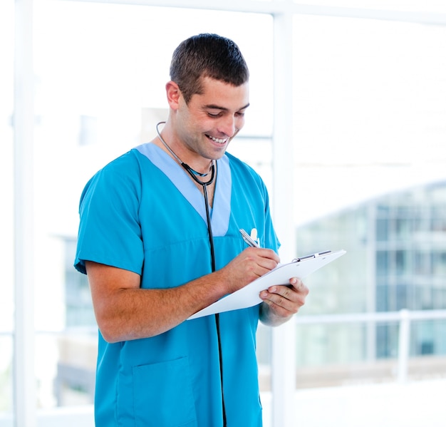 Médico masculino concentrado fazendo anotações na pasta de um paciente