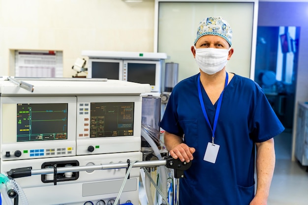 Médico masculino de uniforme azul usa máscara médica nas mãos Fundo claro Trabalhador médico no escritório