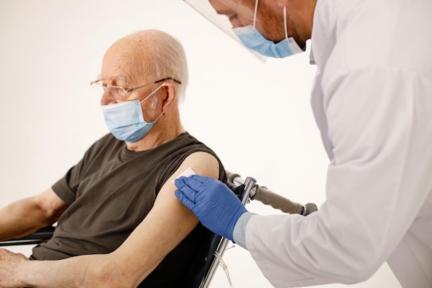 Médico masculino e ancião em cadeira de rodas isolado em um fundo branco