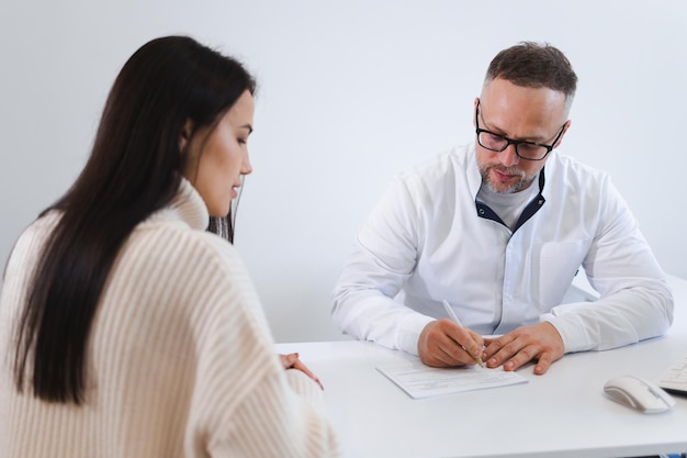 Médico masculino escrevendo uma receita para seu paciente