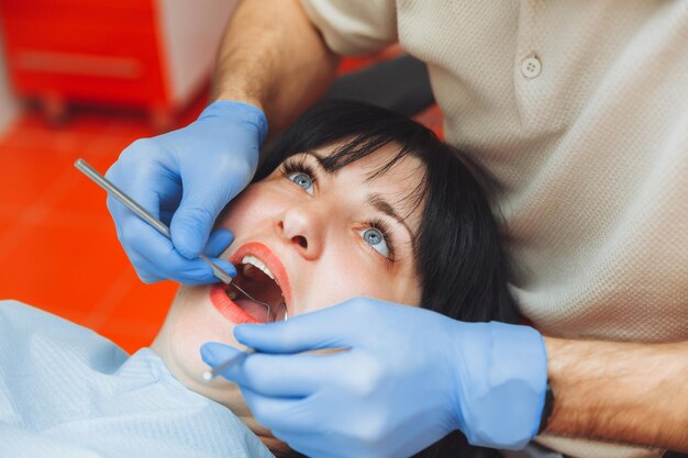 Un médico masculino examina la cavidad oral de un paciente joven sentado en la silla de un dentista en la oficina al lado del dentista el concepto de dientes sanos