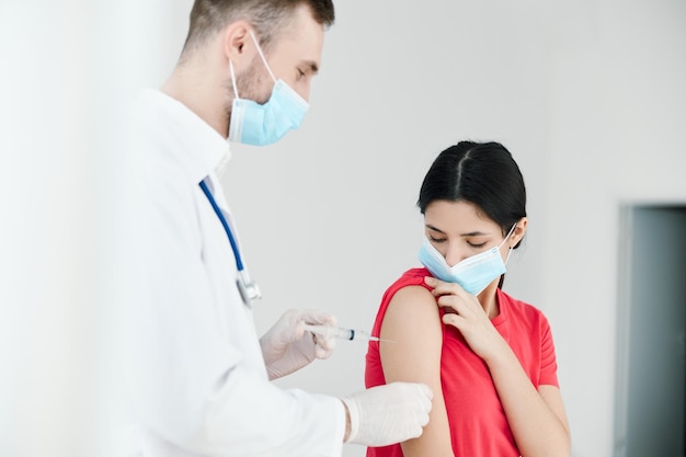 Médico masculino inyectando en el hombro de una mujer coronavirus de salud