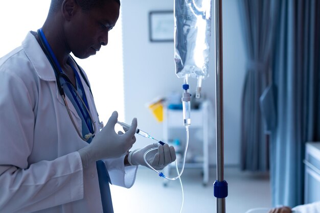 Foto médico masculino inyectando inyección a pacientes femeninas goteo intravenoso en la sala