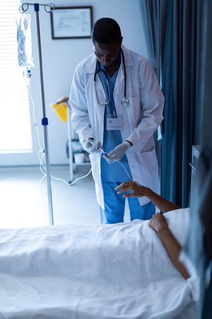 Foto médico masculino inyectando inyección a pacientes femeninas goteo intravenoso en la sala