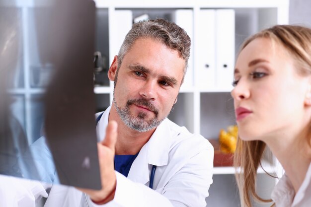 Médico masculino maduro segurar no braço e olhar para a fotografia de raio x