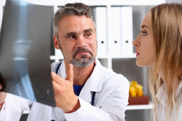 Foto médico masculino maduro segurar no braço e olhar para a fotografia de raio x