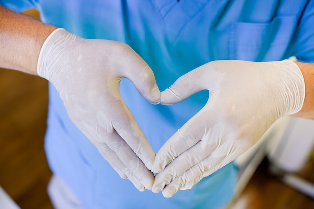 Médico masculino mostrando coração com os dedos