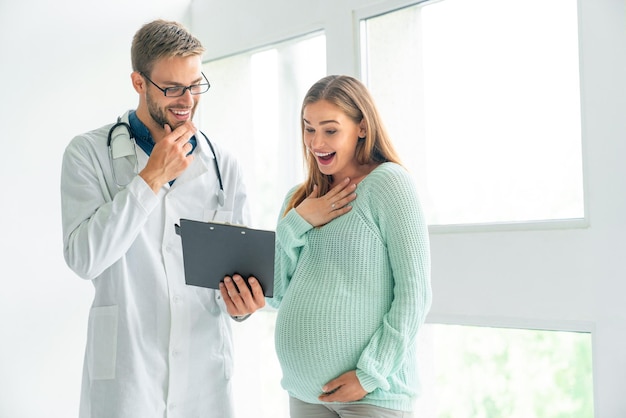 Foto médico masculino mostrando el documento de receta a una mujer embarazada en la clínica