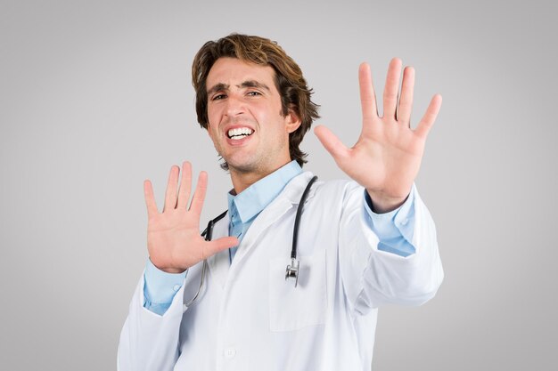 Médico masculino mostrando un gesto de parada con ambas manos pareciendo estresado