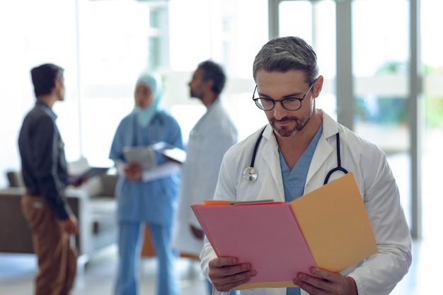 Médico masculino olhando para o arquivo médico no hospital