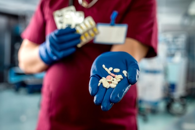 Médico masculino segurando o pacote de comprimidos diferentes no quarto do hospital