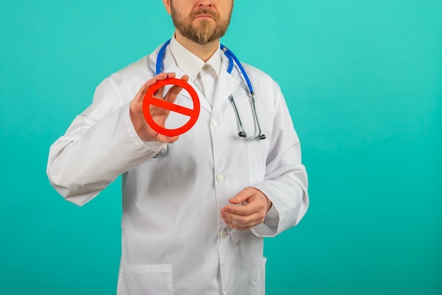 Médico masculino segurando sinal de proibido sobre fundo azul