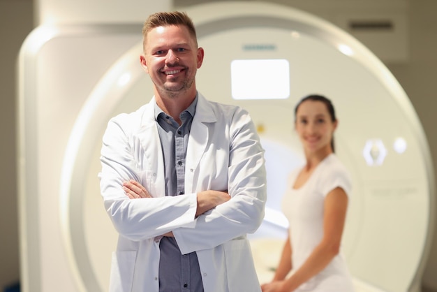 Médico masculino sorridente confiante e paciente do sexo feminino e scanner de tomografia computadorizada em ressonância magnética de fundo