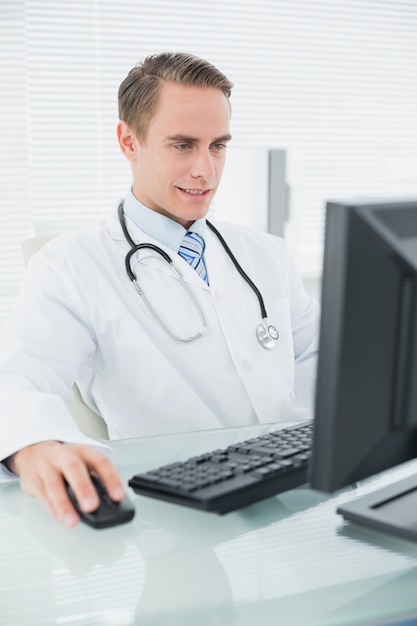 Médico masculino, usando computador, em, escritório médico