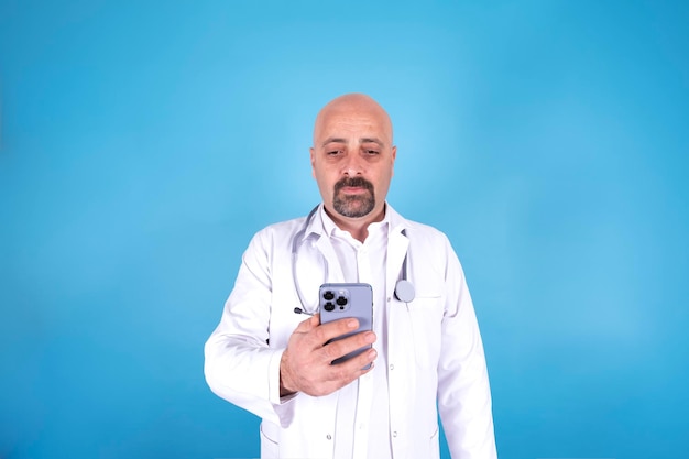 Médico masculino usando médico de smartphone moderno em pé sobre fundo azul