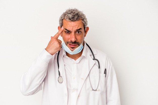 Médico de mediana edad con una máscara para virus aislado de fondo blanco que muestra un gesto de decepción con el dedo índice