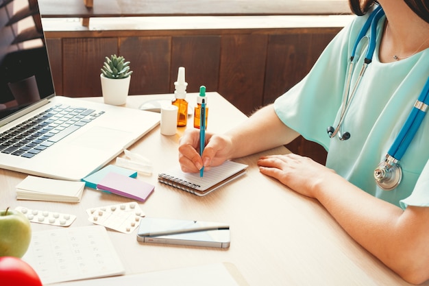 Médico de medicina femenina rellenando el formulario médico del paciente