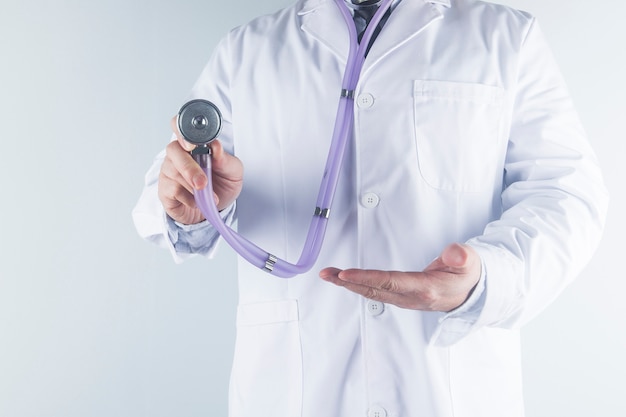 Médico médico en bata de uniforme blanco mano sujetando estetoscopio en clínica hospital.Médico / salud / concepto de tecnología