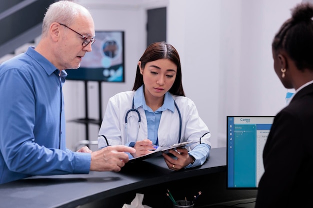 Médico médico mostrando experiência médica para paciente sênior discutindo tratamento medicamentoso durante consulta de consulta de check-up na área de espera do hospital. O especialista está prestando cuidados ao homem doente