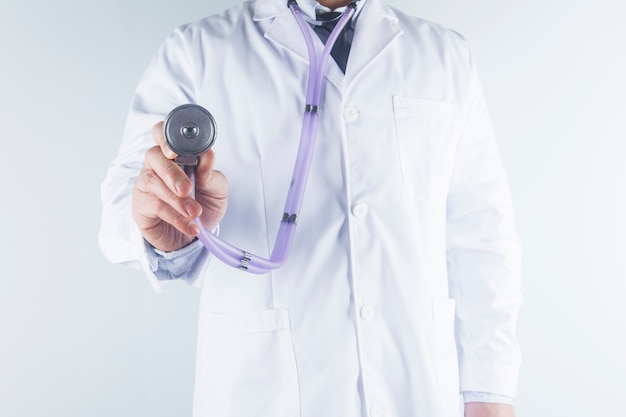 Médico médico na mão de casaco de vestido uniforme branco, segurando o estetoscópio no hospital da clínica.
