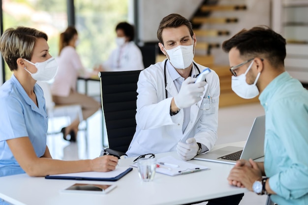 Médico medindo a temperatura do paciente com termômetro infravermelho durante a pandemia de coronavírus