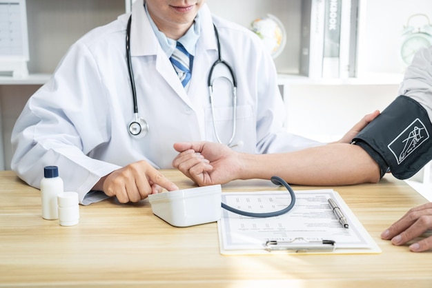 Médico, medindo o paciente de exame e verificando a pressão arterial para diagnóstico de sintomas de doença na clínica do hospital.