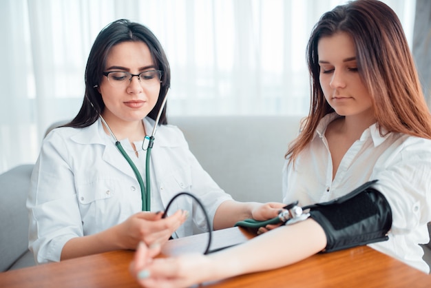 Médico mide la presión corporal de una joven madre