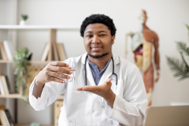 Médico mostrando copo de água no interior do escritório